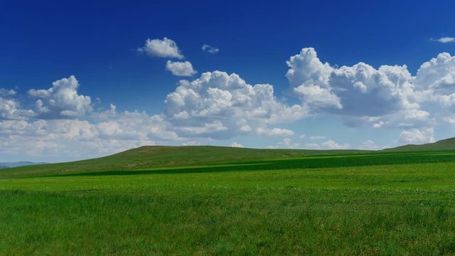 Green hill with grass under cloudy sky, timelapse 4k