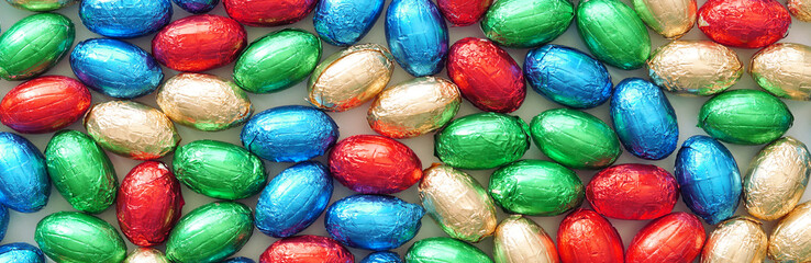 Close-up of pile of colorful candy Easter eggs wrapped in colored foil. colorful candies, panoramic view