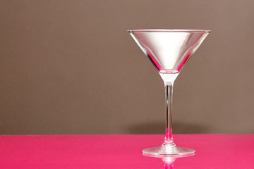 an empty martini glass stands on a bar counter. Background no focus. Close-up
