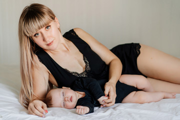 Obraz premium mom and baby in black lying together on bed