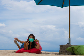 use of medical face mask in public places- young attractive Asian Chinese woman enjoying beach...
