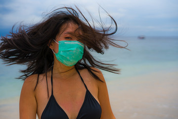use of medical face mask in public places- young attractive Asian Chinese woman enjoying beach...
