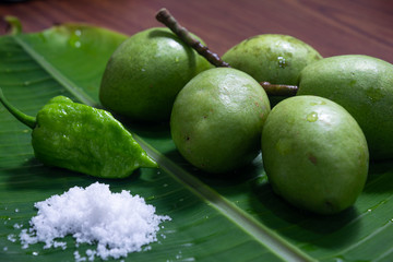 INDIAN OLIVE ZOLPHAI ELAEOCARPUS SERRATUS VERALU CEYLON OLIVE FRUITS WITH GHOST CHILI PEPPER (BHUT JOLOKIA) AND SALT ON A BANANA LEAF CLOSE VIEW 2
