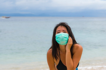 use of medical face mask in public places- young attractive Asian Korean woman enjoying beach...