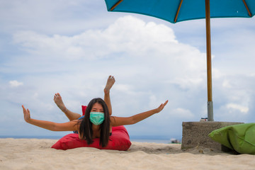 use of medical face mask in public places- young attractive Asian Chinese woman enjoying beach holidays wearing bikini and protective facial mask in prevention vs virus