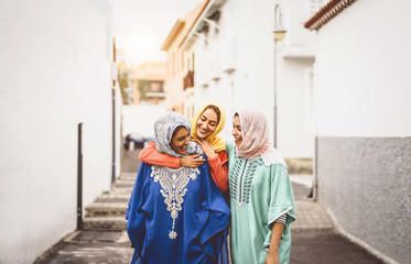 Fototapeta na wymiar Happy Muslim women walking in the city center - Arabian young girls having fun spending time and laughing together outdoor - concept of lifestyle people culture and religion