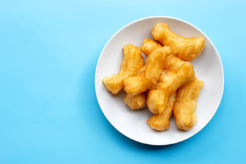 Deep-fried dough stick, chinese bread stick on white dish. Blue background