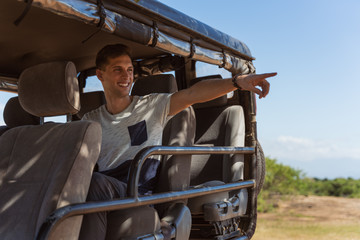 young man pointing wildlife from a safari vehicle © NDStock