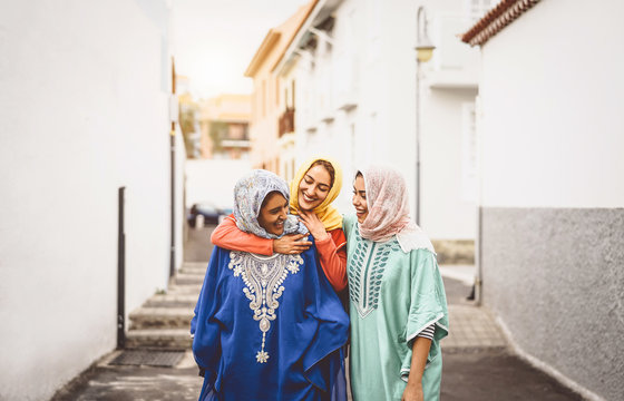 Happy Muslim women walking in the city center - Arabian young girls having fun spending time and laughing together outdoor - concept of lifestyle people culture and religion