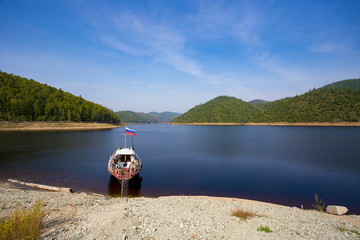 Beautiful landscape. Zeya reservoir, Amur region. 2015. An old boat of the Fish Protection Inspectorate is moored at the reserved shore against the background of green hills.