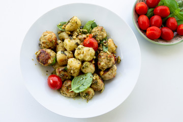 Gnocchi and chicken meatballs with pesto sauce, basil, tomatoes and nuts