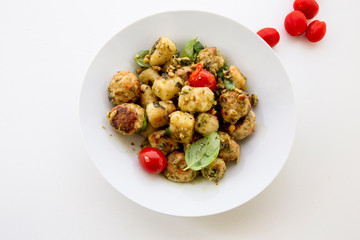 Gnocchi and chicken meatballs with pesto sauce, basil, tomatoes and nuts
