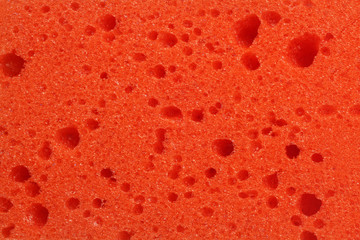 Texture, background of a red sponge for washing dishes or showering close up, macro