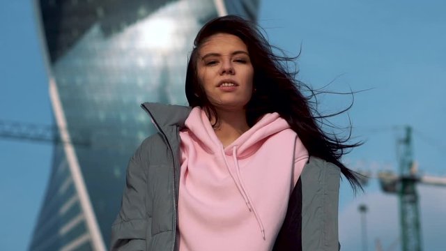 girl against backdrop modern construction site with skyscraper sends kiss camera