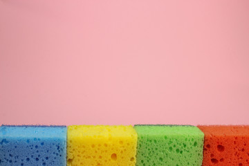 Colorful sponges for washing dishes or cleaning the home on a pink background. Space for text