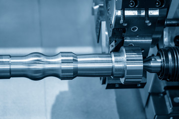 The CNC lathe machine in metal working process forming cutting the metal shaft parts with in the...