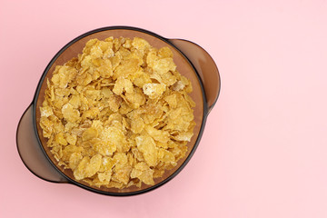 Cornflakes in a glass plate on a pink background