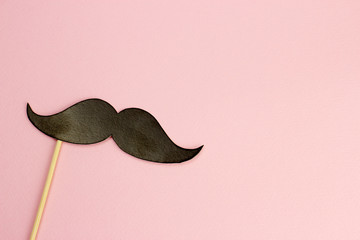 Black mustache on a stick on a pink background. P hoto booth . Space for text