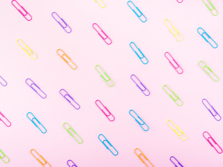 Colorful clips pattern on pink paper background. Stationery flat lay
