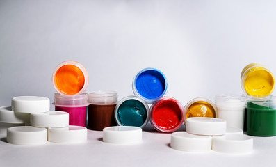 Multi-colored gouache in plastic jars on a white background to create beautiful paintings