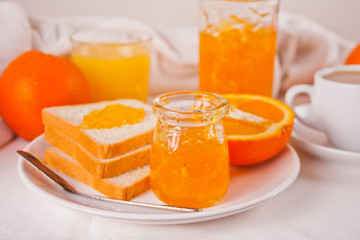 Bread toast with orange jam, glasses of orange juice on the white background. Breakfast concept.