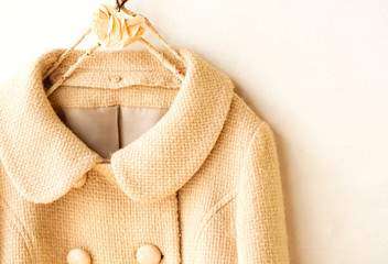 白バックにベージュのコートの肩や襟のクローズアップ