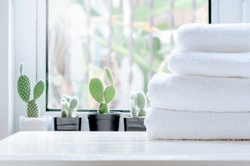 Clean towel on white table near window sill. - obrazy, fototapety, plakaty