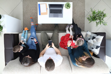 Top view of big family spending time on smartphones. Relatives writing messages and checking social networks on mobiles. Addiction and innovation concept