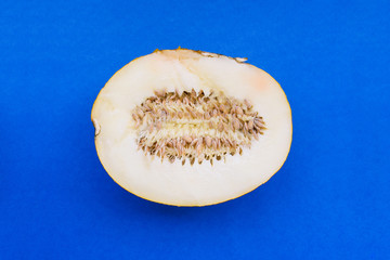 Half ripe melon with seeds on a blue background. Summer ripe vegetable for preparing a healthy meal. Flat lay, top view.