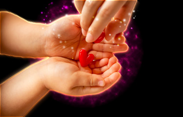 輝く沢山の赤いハートを持つ子供の手と大人の手と黒バックとコピースペース