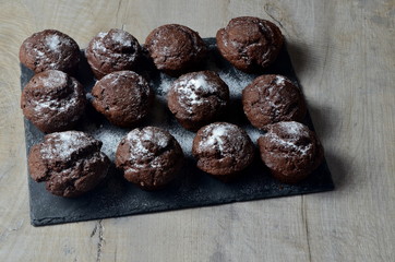 chocolate muffins on black stone plate and gray wood background, place for text