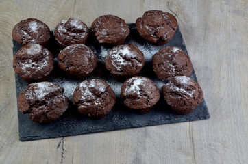 chocolate muffins on black stone plate and gray wood background, place for text