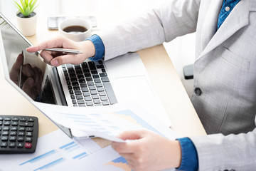 Businessman checking the business reports from the financial imformation from business document and laptop computer. Online business and economy concept.