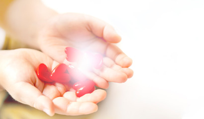 沢山の赤いハートを持つ子供の手とコピースペース