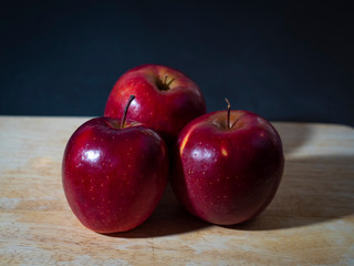 Horizontal photo,three whole red apples on a wood