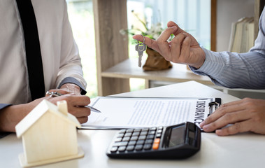 The sales manager or real estate sales representative handed the keys to the customer after signing the contract, signing the lease or buying a house with home loan and home insurance offers