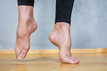 barefoot female feet in black leggings on a wooden floor