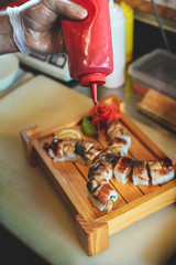 Sushi kitchen. Sushu being made and cut with a chef knife on a white kitchen board.