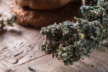 three cookies with marijuana lie on a wooden board. Near big bud cannabis. Horizontal.