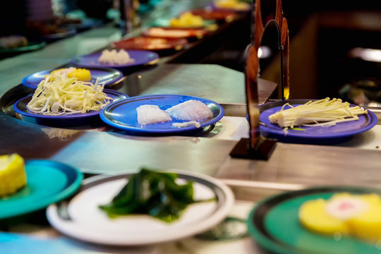 Japan restaurant food conveyor or belt buffet. belt sushi in japan restaurant with blurred background.