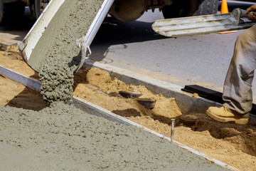 Construction worker pour cement for sidewalk in concrete works with mixer truck with wheelbarrow