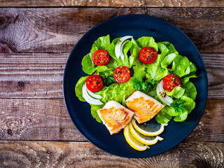 Fish dish - fried cod fillet with vegetables on wooden table