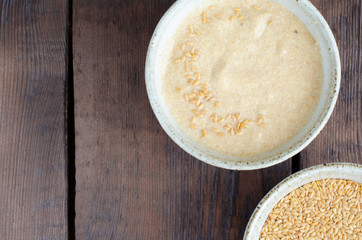 Canadian flax-seeds in bowl and ground linseed with water on wooden background. Top view