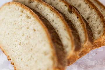 Sliced brown bread on a white tablecloth on the table. Close-up.