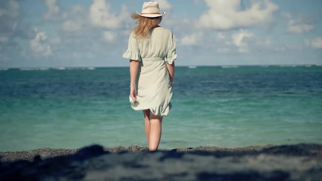 Happy Blond Beautiful Girl Relaxing On Vacation Caribbean Beach.Woman In Hat Walking On Bahamas Ocean Beach.Female Enjoying Travel On Tropical Island.Lady In Dress Sunbathing Exotic Shore On Maldives