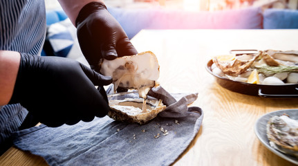 Chef opens a fresh oyster. Dish with open oysters. Restaurant.