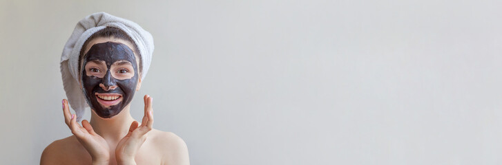 Skincare cleansing eco organic cosmetic spa relax concept. Beauty portrait of young woman in towel on head applying black nourishing mask on face isolated on white background Banner