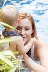 Happy mom with a little son play outdoors. On the background of the pool.