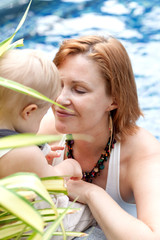 Happy mom with a little son play outdoors. On the background of the pool.