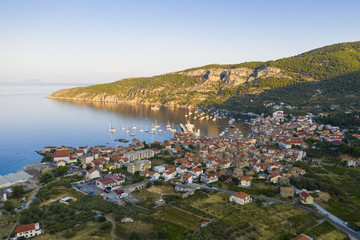 Fototapeta na wymiar Aerial view of Komiza town on Vis island, Croatia in Dalmatia at sunrise. City laying on seaside in Mediterranean Sea surrounded by hills in summer vacation season.